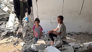 أطفالًا يجلسون بين الأنقاض في طاع غزة، في 5 يوليو 2024.