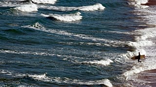 Fransa'nın güneybatısındaki bulunup Atlantik Okyanusu'na açılan Biarritz kentinde bir sörfçü denize giderken görülüyor, 14 Mayıs 2019