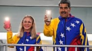 Maduro y la primera dama Cilia Flores encienden las linternas de sus teléfonos móviles tras votar en las elecciones presidenciales en Caracas, Venezuela, en 2024.