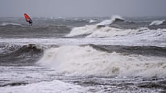 A wind surfer rides on waves at the Baltic Sea near Kuehlungsborn, Germany, Friday, Oct. 20, 2023.