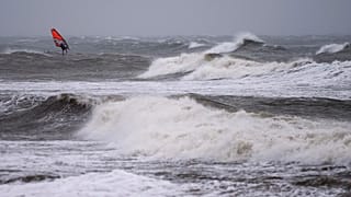 A wind surfer rides on waves at the Baltic Sea near Kuehlungsborn, Germany, Friday, Oct. 20, 2023.