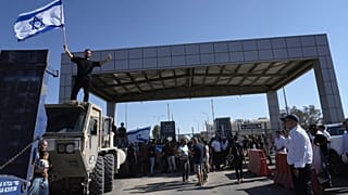 Bir protestocu, Sde Teiman askeri üssünün dışında tutuklulara yönelik kötü muamele nedeniyle sorgulanan askerlere destek olmak için İsrail bayrağını sallarken görüntüleniyor