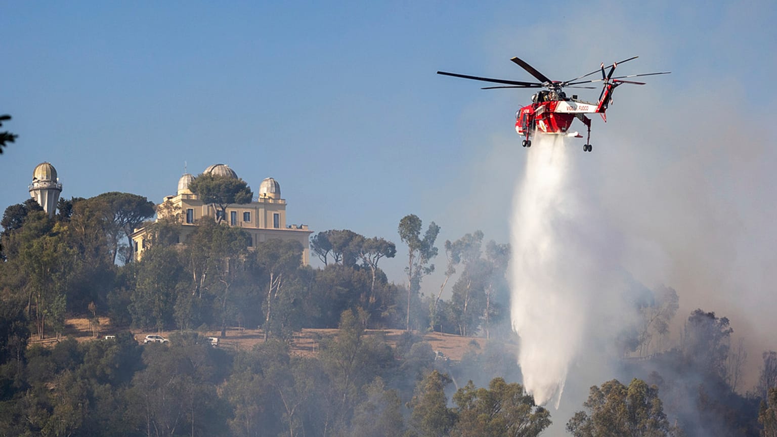 Ein Hubschrauber wirft Wasser auf das Feuer in Monte Mario in Rom.