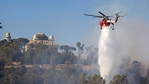 A helicopter drops water over a fire in Monte Mario, behind Piazzale Clodio in Rome, 31 July 2024