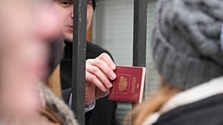 يقوم أمن السفارة الروسية بفحص جوازات سفر المواطنين الروس المصطفين أمام السفارة في وارسو