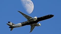 An Air New Zealand passenger plane flies past the moon on its way to the Los Angeles International Airport from London, August 2015.