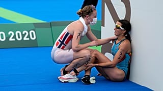 Claire Michel, of Belgium, is assisted by Lotte Miller of Norway after the finish of the women's individual triathlon competition at the 2020 Summer Olympics.