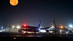 Um avião A380 aterra ao lado de outro A380 enquanto a lua cheia brilha no aeroporto internacional de Frankfurt, Alemanha, no domingo, 13 de outubro de 2019. 