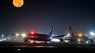 Um avião A380 aterra ao lado de outro A380 enquanto a lua cheia brilha no aeroporto internacional de Frankfurt, Alemanha, no domingo, 13 de outubro de 2019. 