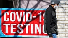 Le panneau d'essai de Covid est affiché dans un magasin alors qu'un piéton passe devant à Chicago, le lundi 11 mars 2024. 