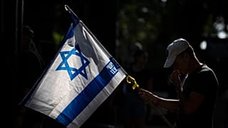 Un hombre sostiene una bandera israelí.