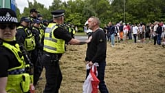 Polizisten stehen Demonstranten vor dem Holiday Inn Express in Rotherham, England, am Sonntag, 4. August 2024, gegenüber.