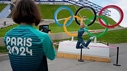 Olympic volunteer Manuella Mallam has her photo taken with the Olympic rings outside Bercy Arena ahead of the 2024 Summer Olympics, Tuesday, July 23, 2024, in Paris, France.