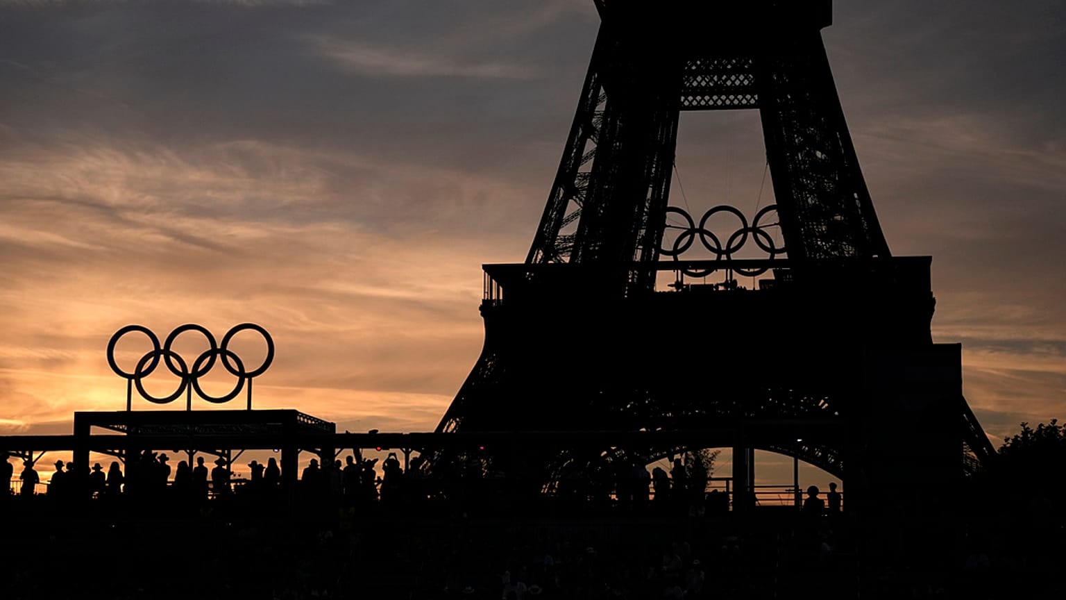 Seyirciler, 6 Ağustos 2024 Salı günü, 2024 Yaz Olimpiyatları'nda Eyfel Kulesi Stadyumu'nda gün batımında Avustralya ve İsviçre arasında oynanan plaj voleybolu çeyrek final maçını izliyor
