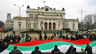 Protesters hold a large Bulgarian national flag and shout slogans during an anti government protest in front of the Bulgarian parliament building in the capital Sofia, 2009.