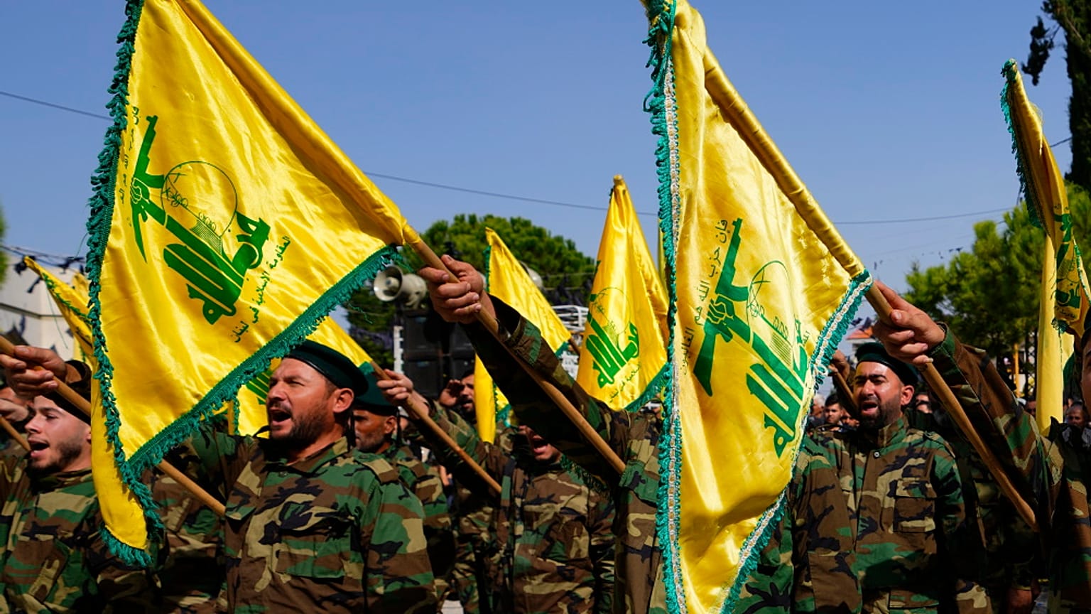 مقاتلو حزب الله يرفعون علم مجموعتهم ويرددون شعارات أثناء حضورهم موكب تشييع في قرية المجادل بجنوب لبنان، الأحد 22 أكتوبر 2023.