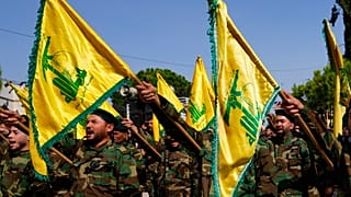مقاتلو حزب الله يرفعون علم مجموعتهم ويرددون شعارات أثناء حضورهم موكب تشييع في قرية المجادل بجنوب لبنان، الأحد 22 أكتوبر 2023.