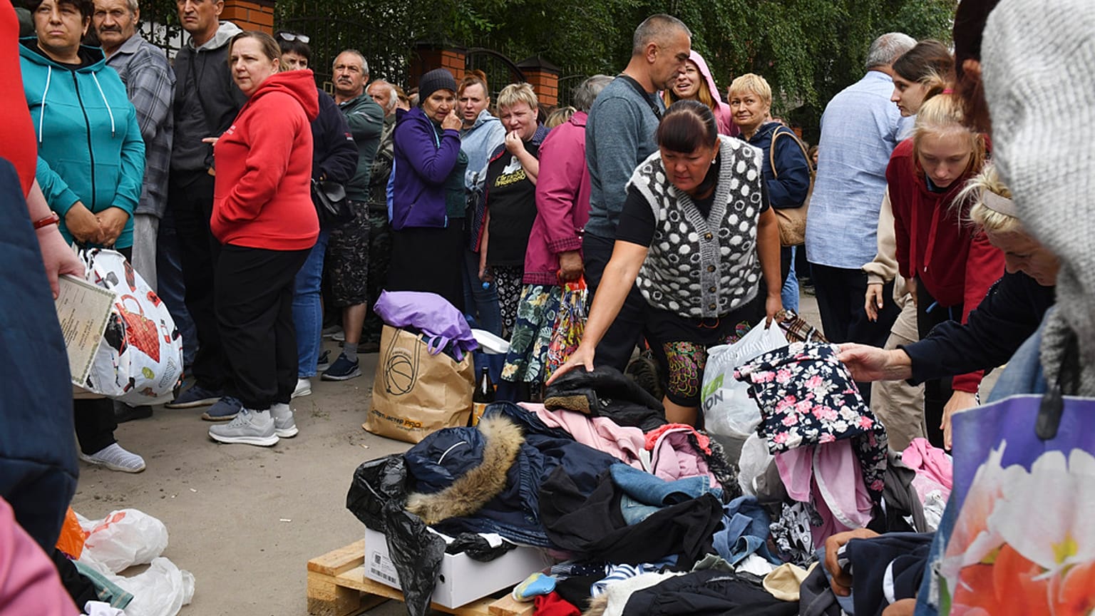 Pessoas fazem fila para receber ajuda humanitária num centro de distribuição em Kursk, Rússia, segunda-feira, 12 de agosto de 2024. 