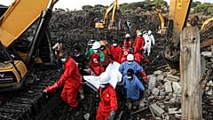 Kızıl Haç personeli, 11 Ağustos 2024 Pazar günü Uganda'nın Kampala kentinde çöken bir çöp sahasında bir kurbanın cesedini taşıyor.