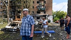 Rusya'nın Kursk kentinde, 11 Ağustos 2024, Pazar günü, Ukrayna tarafından yapılan bombardıman sonrasında hasar gören bir apartmanın yakınında yürüyen insanlar
