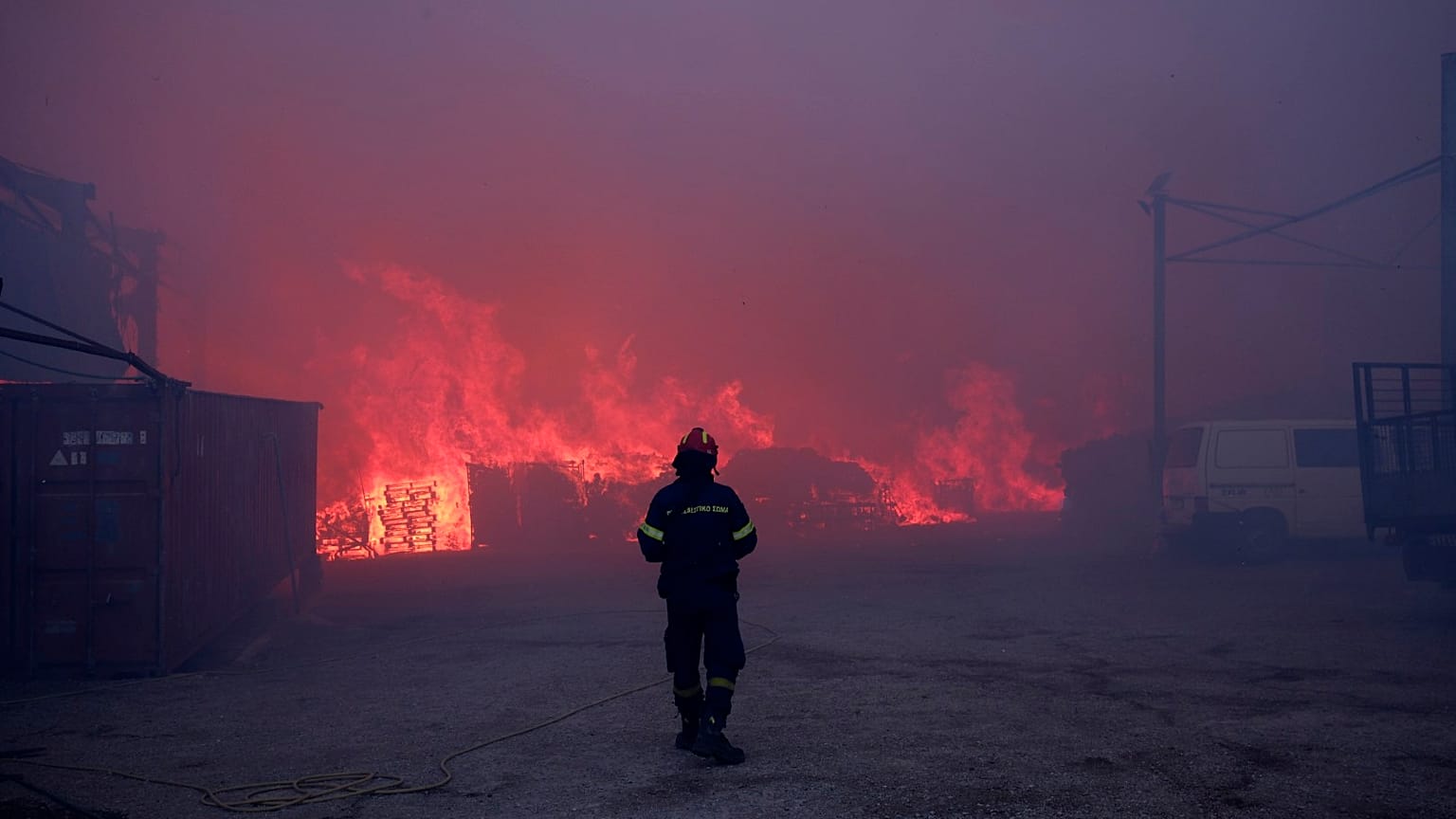 Un pompier se tient devant des bureaux en feu lors d'un incendie dans le nord d'Athènes, le lundi 12 août 2024,