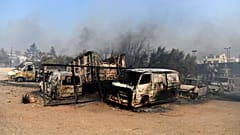 Flames burn a vehicle at a business during a fire in northern Athens, Monday, Aug. 12, 2024,