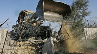 بلدوزر يهدم جزءًا من الجدار الحدودي بين مصر وغزة في رفح، جنوب قطاع غزة، الجمعة، 25 يناير/كانون الثاني 2008. قام مسلحون مدعومون من حماس يقودون جرافات بهدم المزيد من التحصينات 