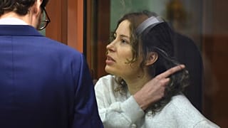 Ksenia Karelina sits in a glass cage in a court room in Yekaterinburg, Russia.