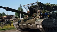 Ein ukrainischer Soldat fährt auf einem Trophäenpanzer, nachdem er aus Russland in der Nähe der russisch-ukrainischen Grenze in der Region Sumy, Ukraine, zurückgekehrt ist.