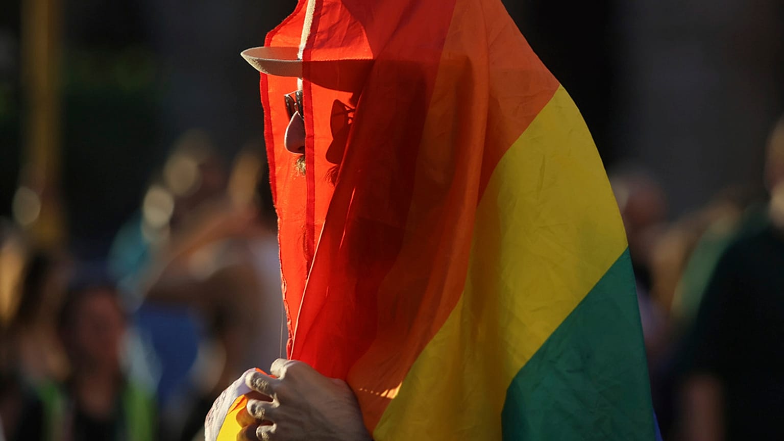 Ein Mensch eingewickelt in eine LGBT-Flagge.