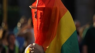 Ein Mensch eingewickelt in eine LGBT-Flagge.