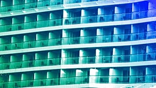 A woman stands on the balcony of a cruise ship which is docked at Athens' port city of Piraeus, July 2024