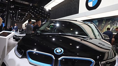 A worker cleans an electric vehicle at the BMW booth during the Auto Shanghai 2019 show in Shanghai on April 17, 2019. (AP Photo/Ng Han Guan, file)