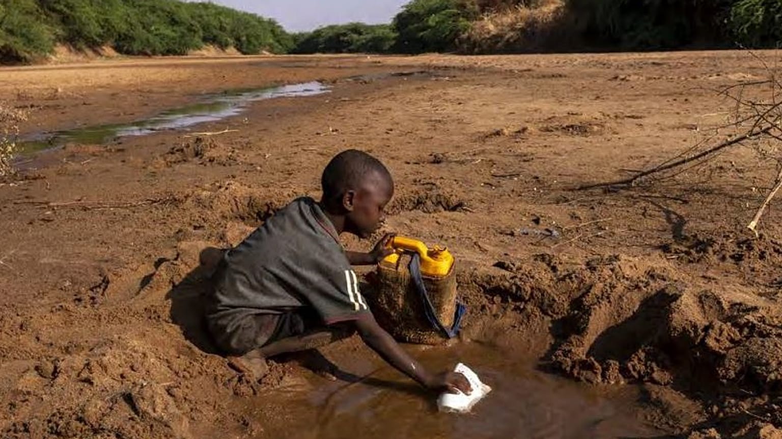 Archivo: Un niño recoge la poca agua que puede de un río seco debido a una grave sequía en Somalia