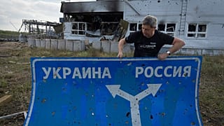 Ukrainian historian Yuri Savchuk, head of the Kyiv-based Ukrainian WWII history museum, carries a road sign in Sudzha, Kursk region, Russia, Friday, Aug. 16, 2024. This image
