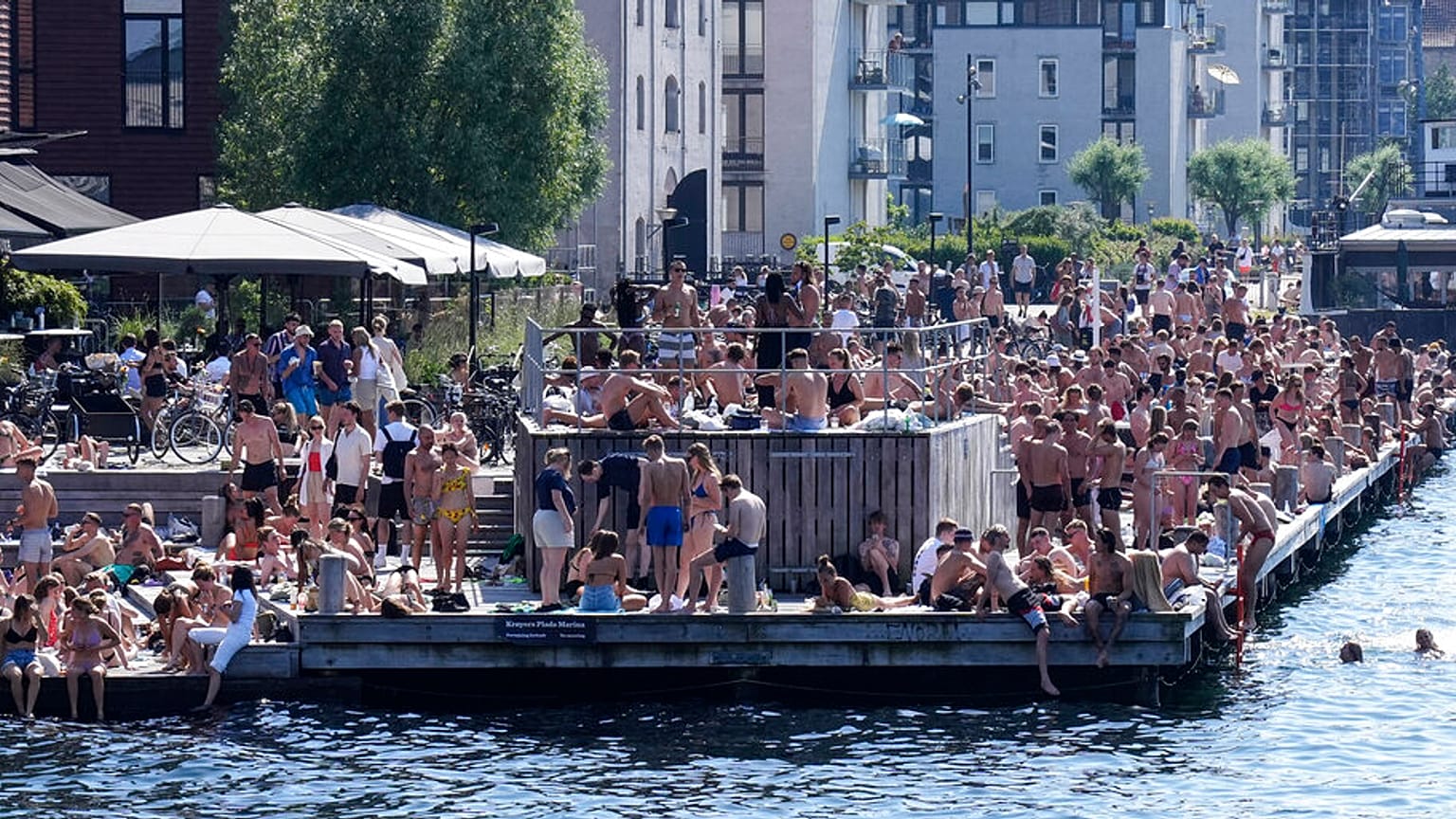 People enjoy sunbathing and refreshment at the harbor in Copenhagen, Denmark, during a hot summer day with temperatures over 30 degrees Celsius, Friday, June 18, 2021.