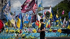 A passer-by looks at a makeshift memorial for fallen Ukrainian soldiers on Independence Square in Kyiv, Ukraine, Tuesday, July 23, 2024. 
