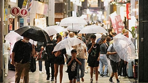 İnsanlar, Pasifik Okyanusu'nda yaklaşan bir tayfun sırasında Tokyo'da bir caddede yürürüyor, 16 Ağustos 2024.