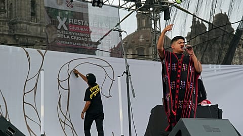 O artista mexicano-triqui Carlos CGH, vestindo um “gabán” preto e vermelho, uma peça de vestuário nativa do povo Triqui,  na Cidade do México, terça-feira, 6 de agosto de 2024