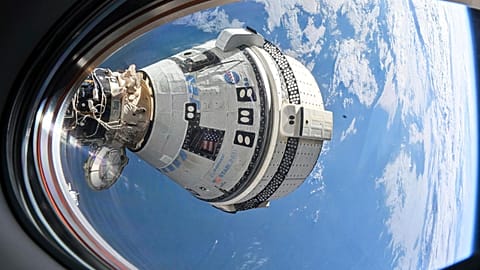 Boeing's Starliner spacecraft seen from a window on the SpaceX Dragon Endeavour spacecraft docked to the adjacent port.