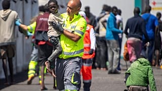 Un bambino viene assistito da un membro della squadra di emergenza dopo essere stato salvato da una barca nel porto di La Restinga, sull'isola canaria di El Hierro