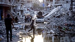 FILE - Palestinians displaced by the Israeli air and ground offensive on the Gaza Strip, walk past sewage flowing into the streets of the southern town of Khan Younis.