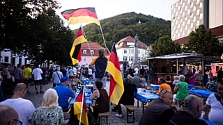 People wave German national flags as they listen to Bjoern Hoecke, top candidate of the far-right Alternative for Germany party, or AfD, during an election campaign rally.