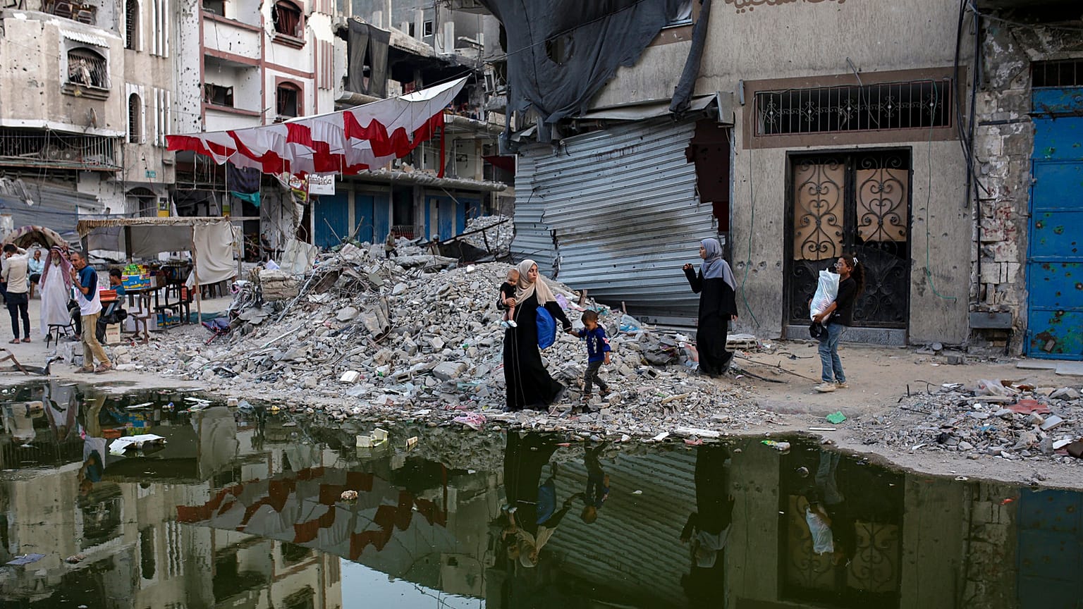 Palästinenser, die durch die israelische Luft- und Bodenoffensive auf den Gazastreifen vertrieben wurden, gehen neben einem dunklen Streifen von Abwässern, die in die Straßen der südlichen Stadt Khan Younis fließen