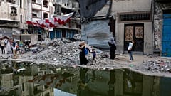 Palästinenser, die durch die israelische Luft- und Bodenoffensive auf den Gazastreifen vertrieben wurden, gehen neben einem dunklen Streifen von Abwässern, die in die Straßen der südlichen Stadt Khan Younis fließen