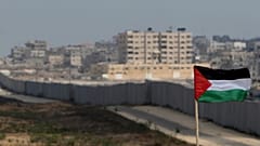 علم فلسطين يرفرف على خلفية قسم من الجدار في ممر فيلادلفيا بين مصر وغزة. الأحد 1 يوليو/تموز 2007