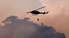Symbolbild: Ein Hubschrauber wirft Wasser über einem Feuer in Tjentiste, Bosnien, Dienstag, 13. August 2024, ab.