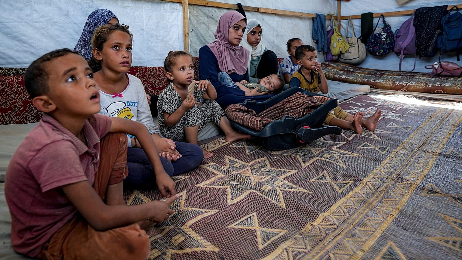 Abdel-Rahman Abu El-Jedian, de 11 meses, enfermo de poliomielitis, es llevado en brazos por su madre en un campamento improvisado en Deir al-Balah.