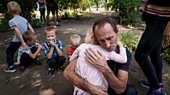 Un padre abraza a su hija, con sus otros hijos cerca, mientras la familia espera a ser evacuada en Pokrovsk, región de Donetsk, Ucrania, 23 de agosto de 2024.