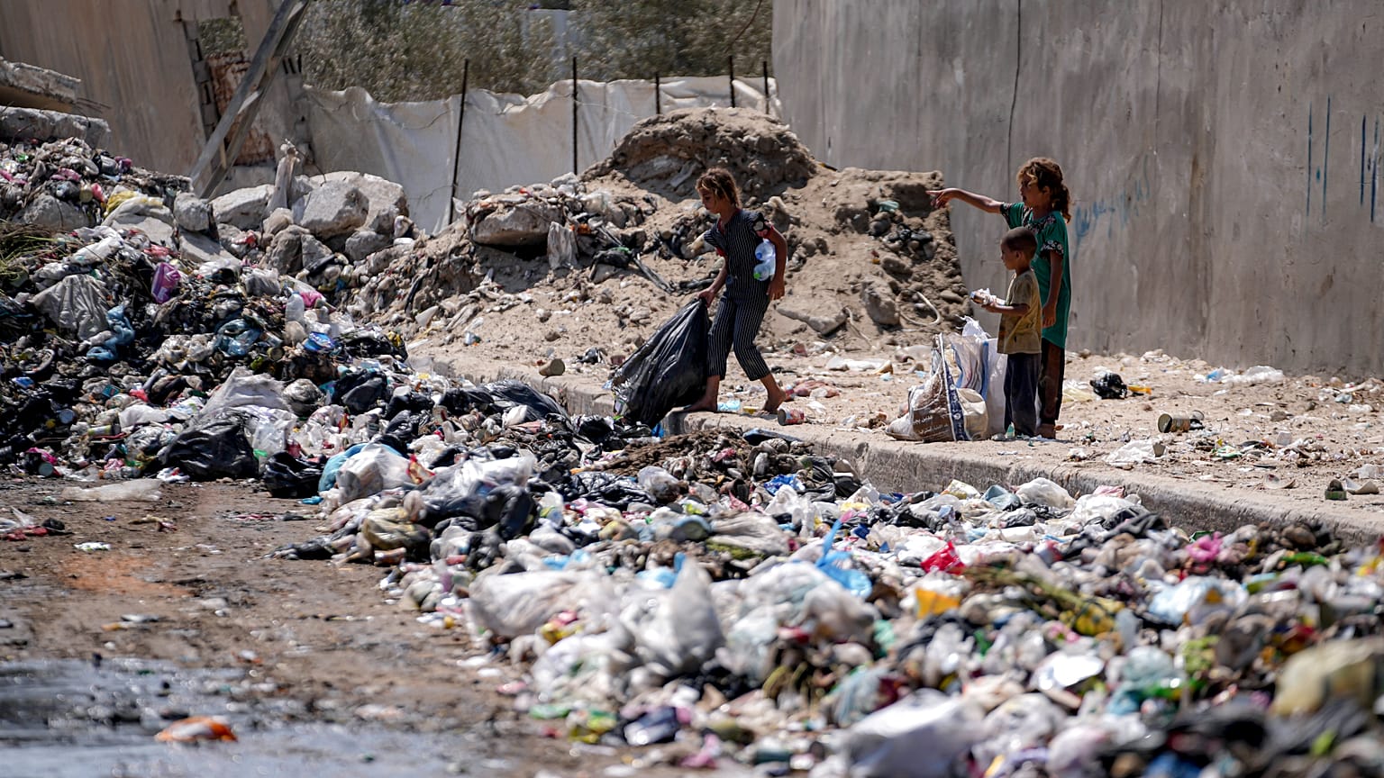 أطفال نازحون يفرزون القمامة في أحد شوارع دير البلح وسط قطاع غزة، الثلاثاء، 27 أغسطس/آب 2024